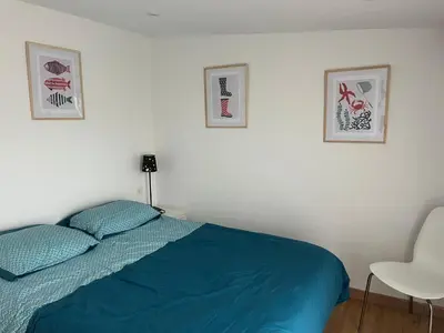 a bedroom with a bed and two pictures on the wall at Mini villa au bord de la mer, proche Moriani (Corse) in Poggio-Mezzana