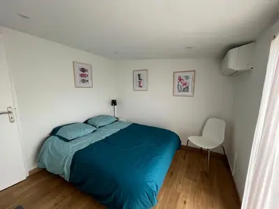 a bedroom with a blue bed and a white chair at Mini villa au bord de la mer, proche Moriani (Corse) in Poggio-Mezzana
