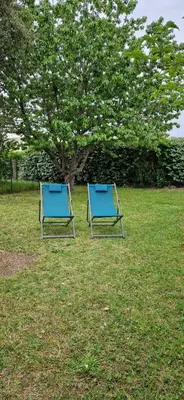 two blue chairs sitting in the grass near a tree at Mini villa au bord de la mer, proche Moriani (Corse) in Poggio-Mezzana