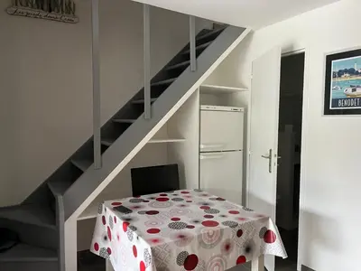 a white room with a table and a staircase at Mini villa au bord de la mer, proche Moriani (Corse) in Poggio-Mezzana