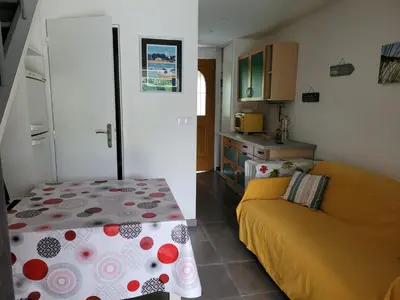 a living room with a yellow couch and a kitchen at Mini villa au bord de la mer, proche Moriani (Corse) in Poggio-Mezzana