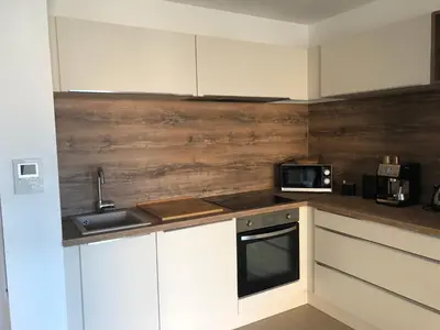 a kitchen with white cabinets and a wooden wall at Fronte di Mare in Propriano