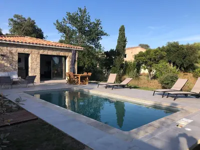 a swimming pool with two chairs and a table at Villa Ucellu sur 600 m2 avec accès mer privilégié et piscine privée chauffée in Sainte-Lucie de Porto-Vecchio