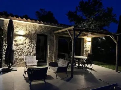 a patio with chairs and a table and an umbrella at Villa Ucellu sur 600 m2 avec accès mer privilégié et piscine privée chauffée in Sainte-Lucie de Porto-Vecchio
