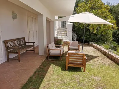 a patio with a bench and an umbrella and chairs at Villa Via serena in Ajaccio