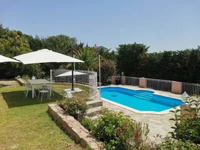 a swimming pool with a table and an umbrella at Villa Via serena in Ajaccio