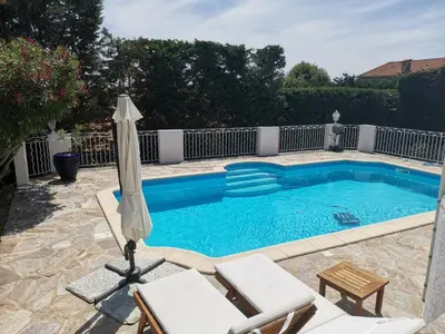 a swimming pool with an umbrella and two chairs and a table at Villa Via serena in Ajaccio