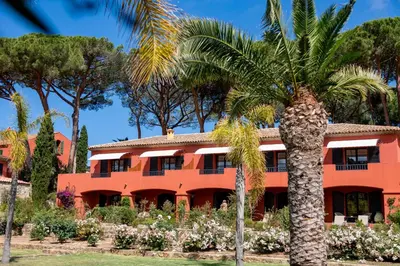 an orange building with palm trees in front of it at La Signoria & Spa in Calvi