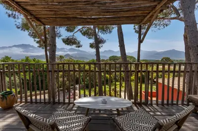 a patio with a table and chairs and mountains in the background at La Signoria & Spa in Calvi