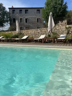 a swimming pool with benches and umbrellas in front of a building at Domaine de Tappa - Casa Filicina in Sollacaro