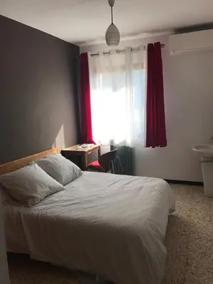 a bedroom with a bed and a window with a red curtain at U Ricordu in Prunelli-di-Fiumorbo