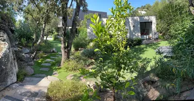 a garden with trees and a building with a yard at Pavillon de la Trinité in Porto-Vecchio