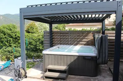 a hot tub under a pergola on a patio at Chalet zen in Peri