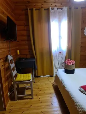 a bedroom with a bed and a chair and a window at Chalet zen in Peri