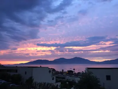 a sunset over a body of water with buildings at Appart 8 pers vue sur baie - Porticcio in Porticcio