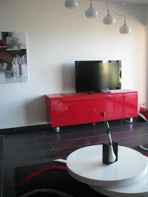 a living room with a red entertainment center with a tv at Appart 8 pers vue sur baie - Porticcio in Porticcio