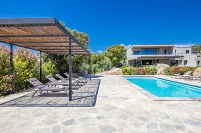 a swimming pool with lounge chairs next to a house at Villa 19 in Zonza