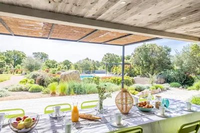 a table with food on it with a view of a garden at Villa 19 in Zonza