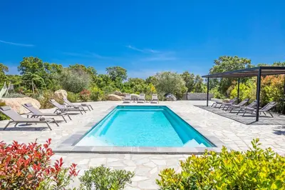 a swimming pool with lounge chairs and a pavilion at Villa 19 in Zonza