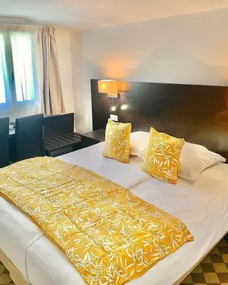 a hotel room with a large bed with yellow sheets and pillows at Si Mea in Corte