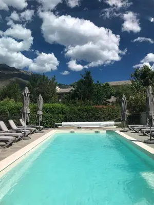 a swimming pool with chaise lounge chairs and a blue sky at Si Mea in Corte