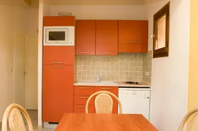 a kitchen with orange cabinets and a table with chairs at Résidence Padro in Calvi