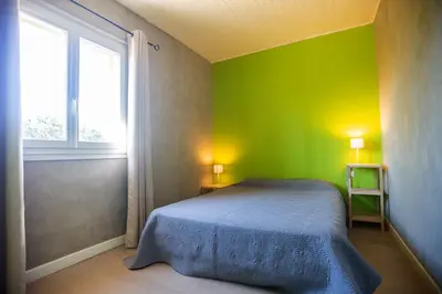 a green bedroom with a bed and a window at Résidence Padro in Calvi