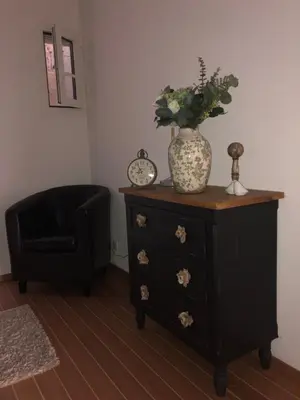 a black dresser with a vase on top and a chair at VILLA GOLFE AJACCIO près des plages in Ajaccio