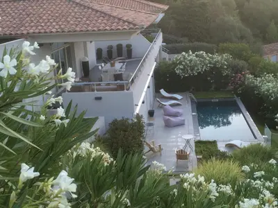 a white house with a swimming pool and flowers at VILLA GOLFE AJACCIO près des plages in Ajaccio