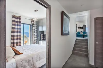 a bedroom with a bed and a hallway with a staircase at Villa No Stress Aria di Petra in Olmeto