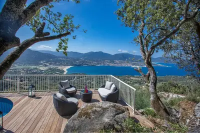 a deck with chairs and a view of a lake at Villa No Stress Aria di Petra in Olmeto