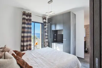 a bedroom with a bed and a large window at Villa No Stress Aria di Petra in Olmeto