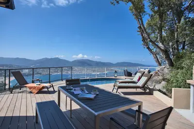 a deck with a table and chairs and a pool at Villa No Stress Aria di Petra in Olmeto