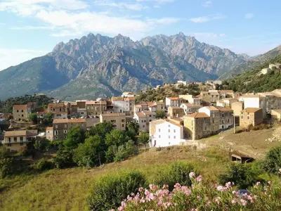 a village on a hill with mountains in the background at Maison de village in Moltifao