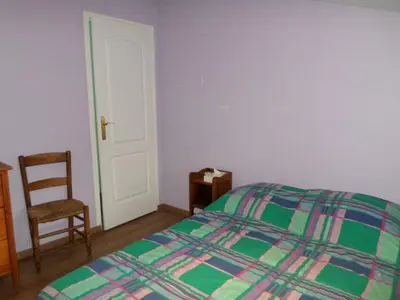 a bedroom with a bed and a chair and a door at Maison de village in Moltifao