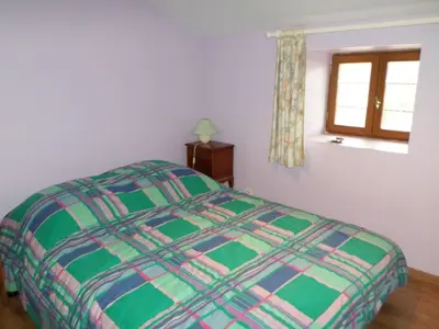 a bed in a bedroom with a window and a bedspread at Maison de village in Moltifao