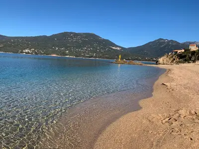 a beach with water and mountains in the background at T3 vue mer in Propriano