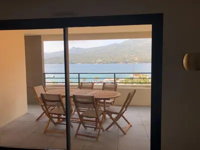 a table and chairs on a balcony with a view of the water at T3 vue mer in Propriano