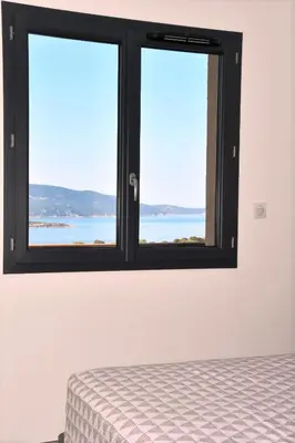 a bedroom with a window with a view of the ocean at Cosy vue mer in Olmeto