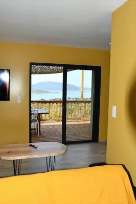 a room with a bed and a table and a balcony at Cosy vue mer in Olmeto