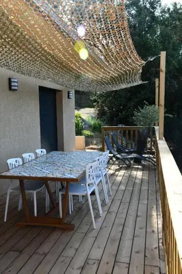a patio with a table and chairs on a deck at Cosy vue mer in Olmeto