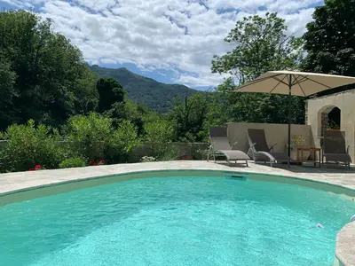 a swimming pool with an umbrella and a table and chairs at LA SOURCE 4 chambres in Valle d'Alesani