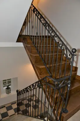 a wooden staircase with black railings in a house at LA SOURCE 4 chambres in Valle d'Alesani