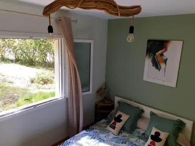 a bedroom with a bed next to a window at Autour du Hamac chambres et table d'hôtes in Moltifao
