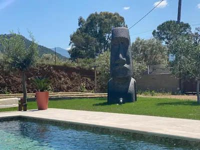 a statue sitting next to a pool next to a yard at APICULTEUR in Oletta