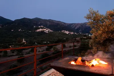 a fire pit with a view of the mountains at APICULTEUR in Oletta