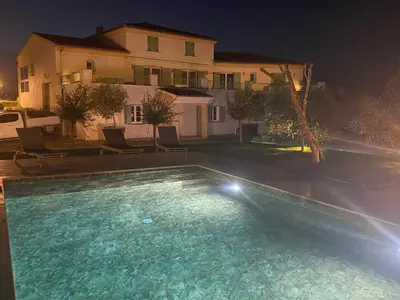 a swimming pool in front of a house at night at APICULTEUR in Oletta