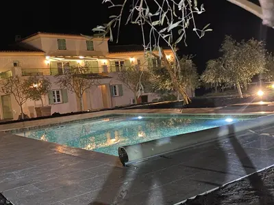 a swimming pool in front of a house at night at APICULTEUR in Oletta