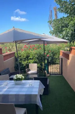 a patio with two tables and an umbrella at Les Maisonnettes de Lava - Golfe de Lava - APPIETTO in Appietto