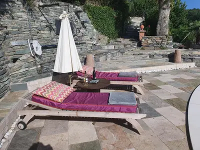 two lounge chairs with a table and an umbrella at maison de charme avec piscine et vue exceptionnelle in Scolca